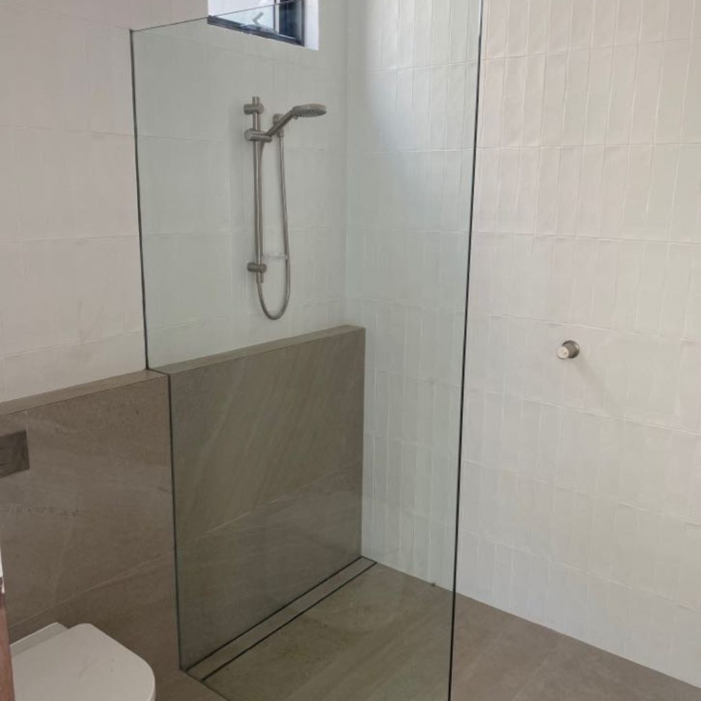 Modern bathroom featuring sleek frameless shower screens with a minimalistic design, enhancing the space's elegance and openness.