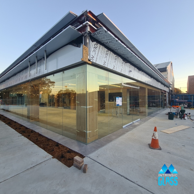 commercial glass replacement with large frameless sliding glass doors on a modern building corner.
