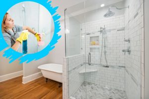 A well-maintained bathroom with clean glass shower screens, showcasing a pristine white-tiled shower area with modern fixtures. An inset image highlights a person cleaning a glass shower screen with a blue cleaning spray and a pink cloth, demonstrating effective cleaning techniques for spotless glass surfaces.