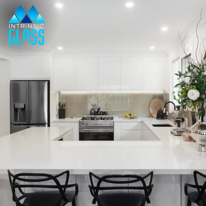 a modern kitchen with a stainless steel stove and refrigerator and a glass splashback in Balmoral behind the stove.