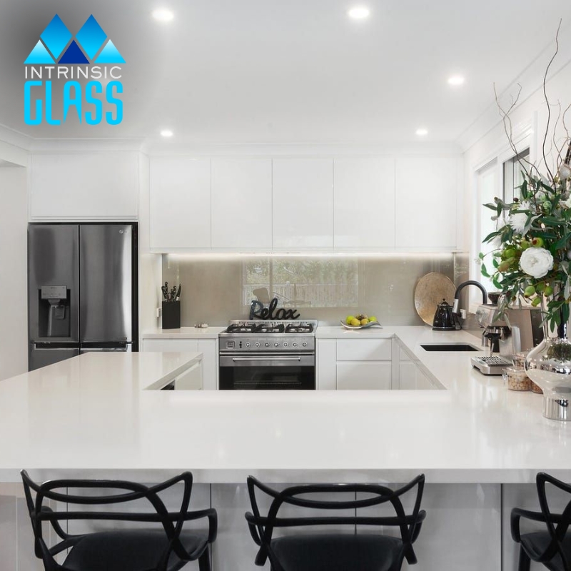 a modern kitchen with a stainless steel stove and refrigerator and a glass splashback in Wangi Wangi behind the stove.