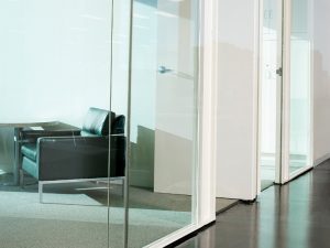 Modern office interior with a clear glass partition, creating separate work areas.