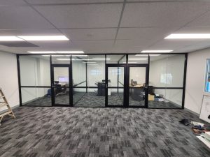 Black-framed glass partitions optimising office space by creating functional, professional meeting rooms and individual workspaces.