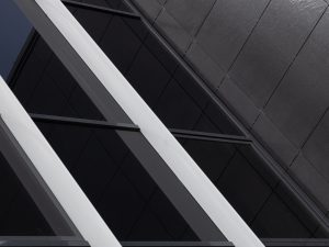 Black glass wall with a white frame, reflecting the sky and creating a geometric pattern.