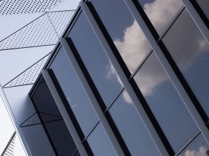 Black glass wall with a geometric pattern and reflections of clouds.