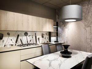 Contemporary kitchen featuring white frosted glass splashback with black utensil graphics, light timber cabinets and marble dining table.