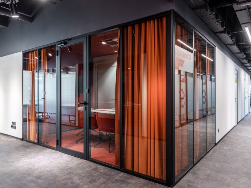 Sleek office space with full-length half glass partition and curtains, blending modern design with privacy features.