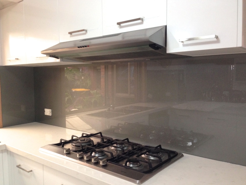 Grey splashback seamlessly installed behind gas cooktop in modern kitchen
