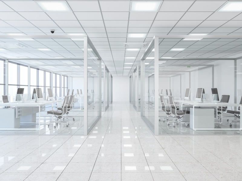 Office division walls with floor-to-ceiling glass panels dividing meeting rooms and desks in a bright open-plan office