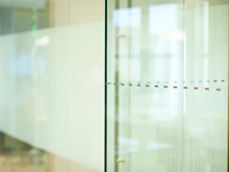 Frosted glass partitions with small square cut-out accents in workplace.