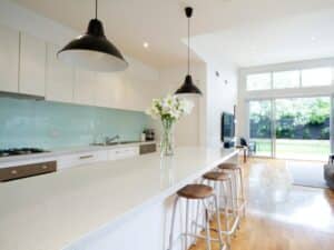 open-plan kitchen with mint green glass splashbacks colours and pendant lights above a long island bench