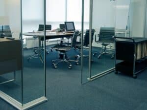 Sleek office interior with transparent glass room separator and modern furniture